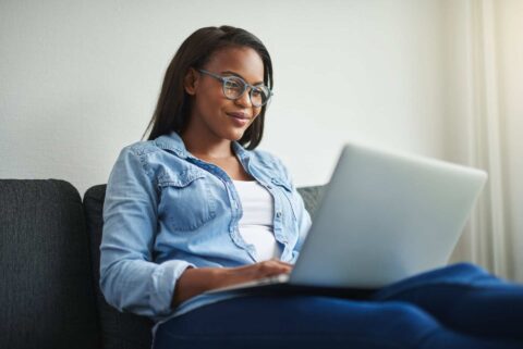 Frau sitzt entspannt mit Laptop auf dem Sofa – Symbol für digitalen Kundenservice und bequeme Energieverwaltung.