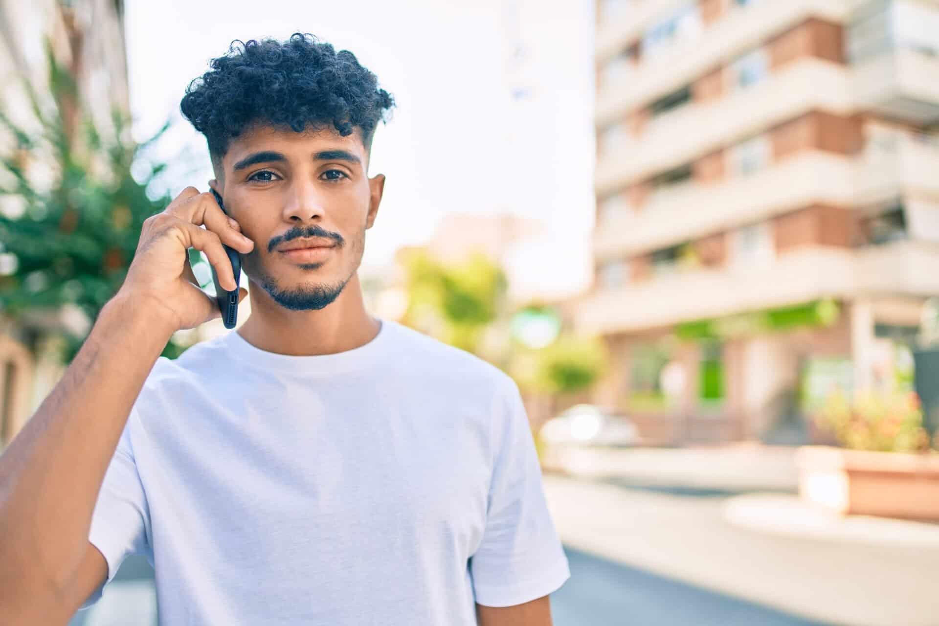 Junger Mann telefoniert im Freien – Symbol für eine Störungsmeldung oder Notfallkontakt mit dem Versorger.