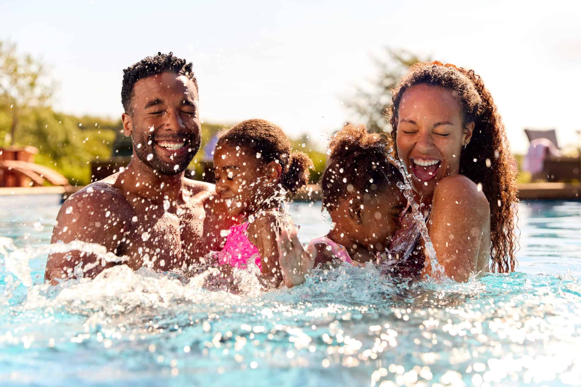 Familie mit zwei Kindern planscht lachend im Freibad – Symbol für Sommer, Spaß und gemeinsame Zeit.