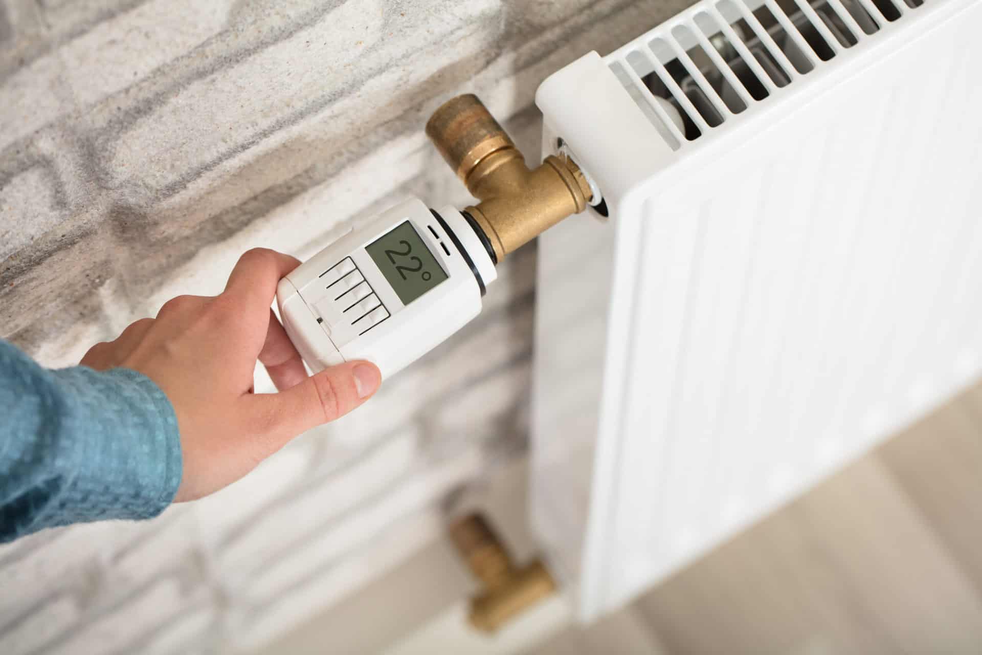 Hand stellt ein digitales Thermostat auf 22 Grad ein – Symbol für moderne Heiztechnik und individuelle Wärme.