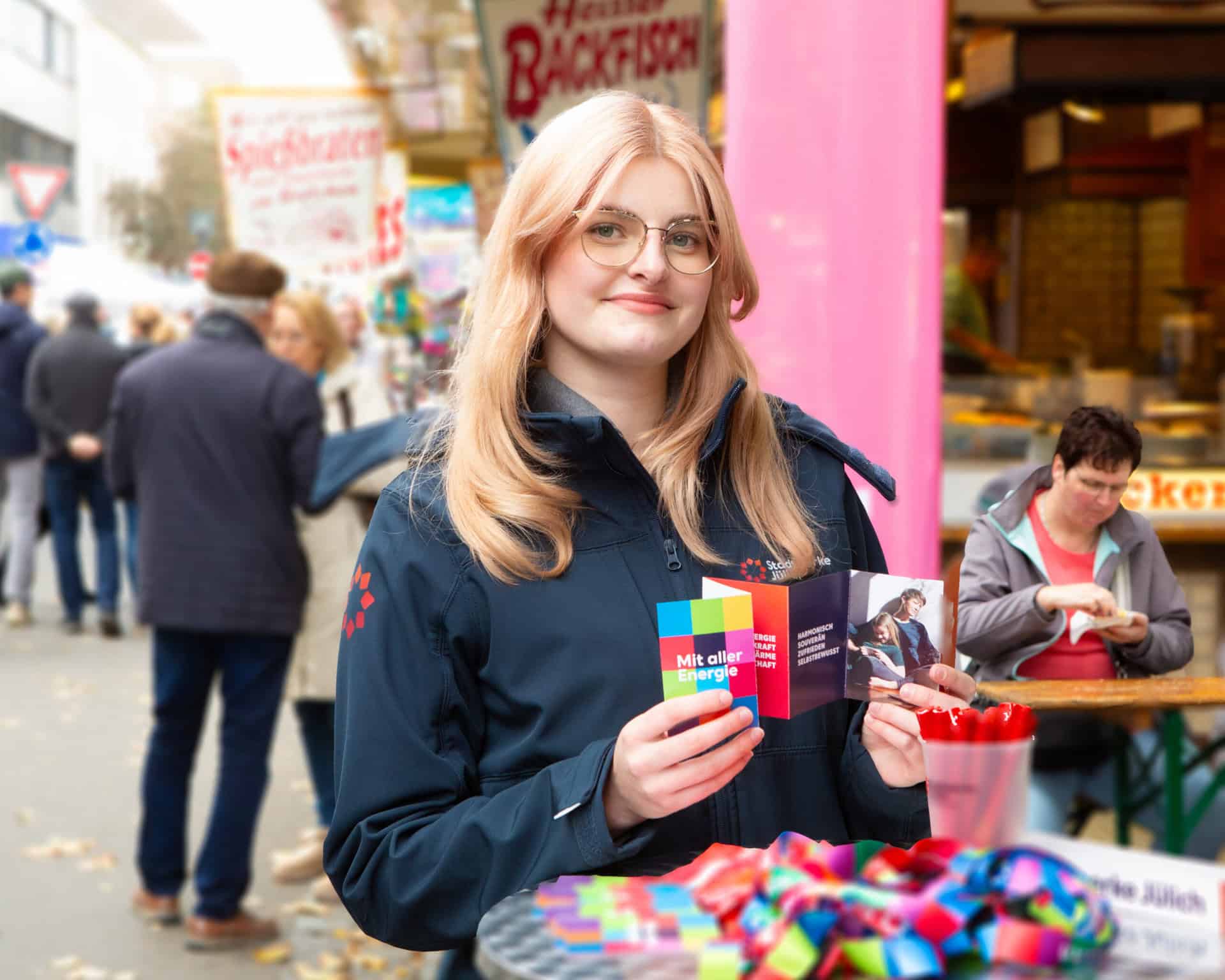 Mitarbeiterin der Stadtwerke Jülich mit Flyern an einem Informationsstand auf einer öffentlichen Veranstaltung.
