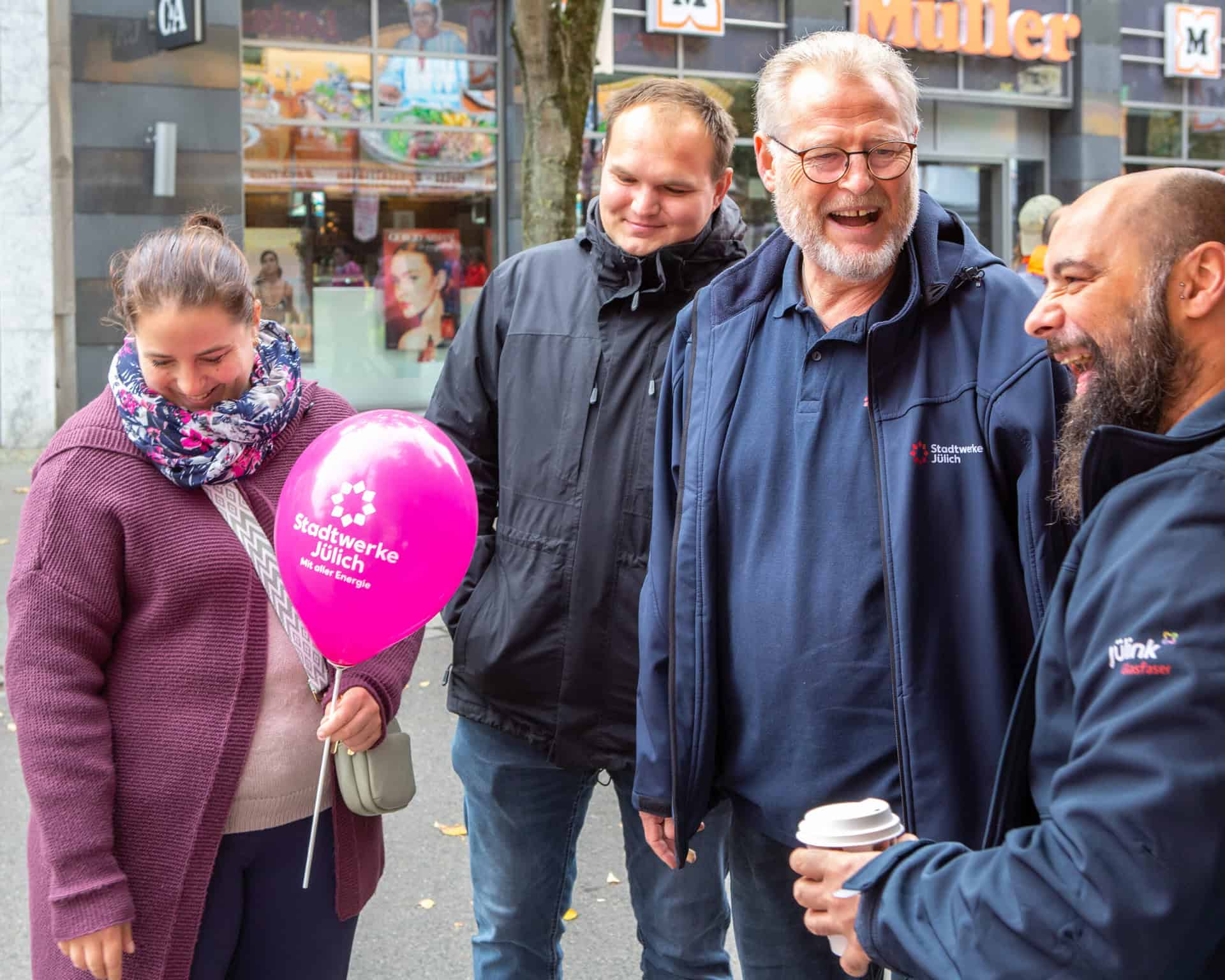 Mitarbeitende der Stadtwerke Jülich im Gespräch mit gut gelaunten Besucher:innen einer Veranstaltung.