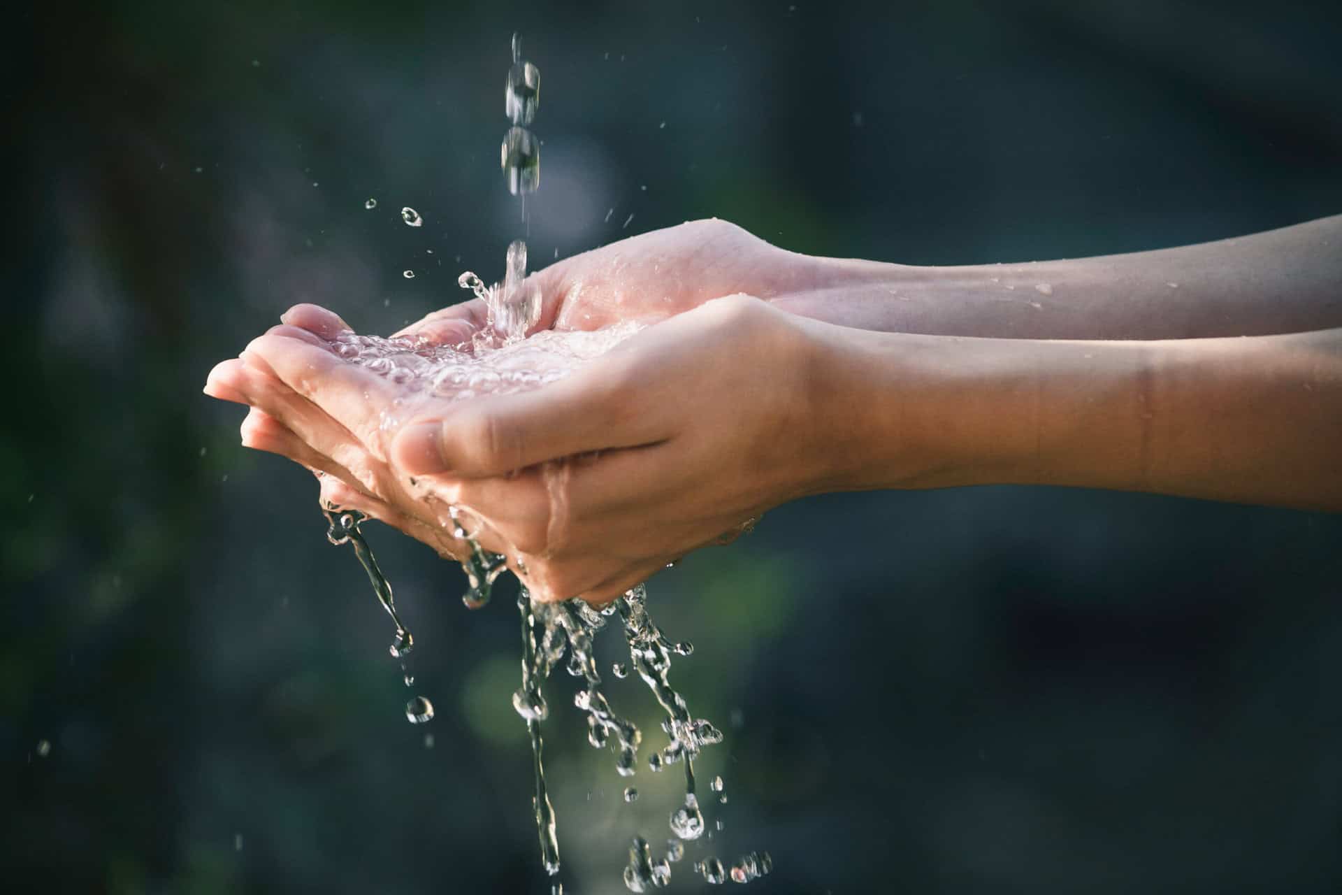 Hände fangen frisches Wasser auf – Symbol für den Wert und die Verfügbarkeit von Trinkwasser.