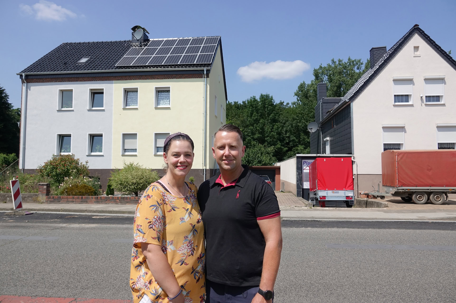 Ein junges Paar steht vor seinem Haus mit installierter Photovoltaikanlage – Symbol für persönliche Energiewende und Unabhängigkeit.