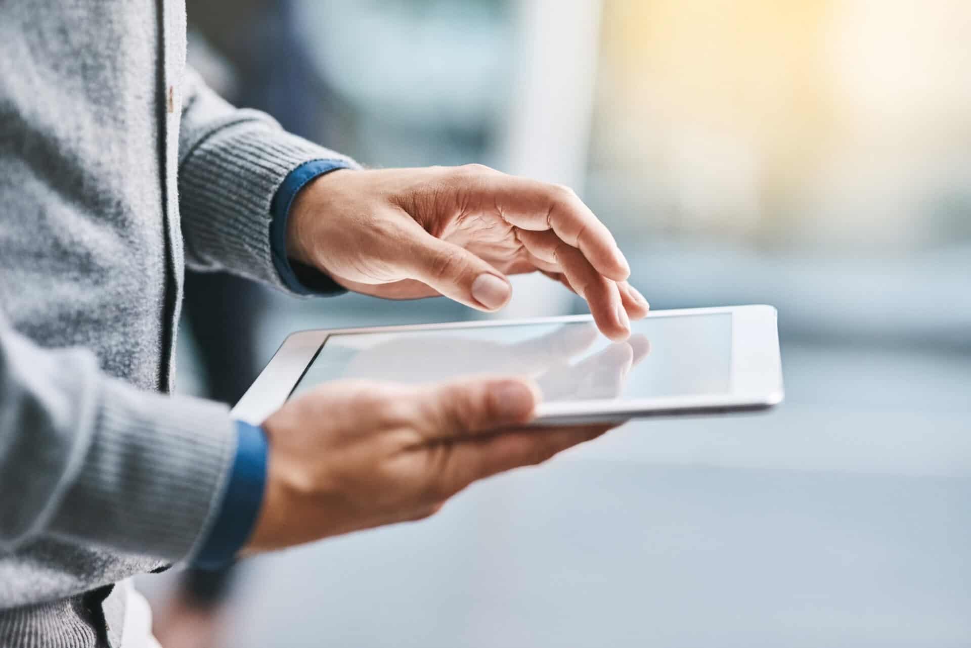 Person hält ein Tablet in der Hand und nutzt es per Touch – symbolisch für digitalen Zugriff auf Medieninhalte
