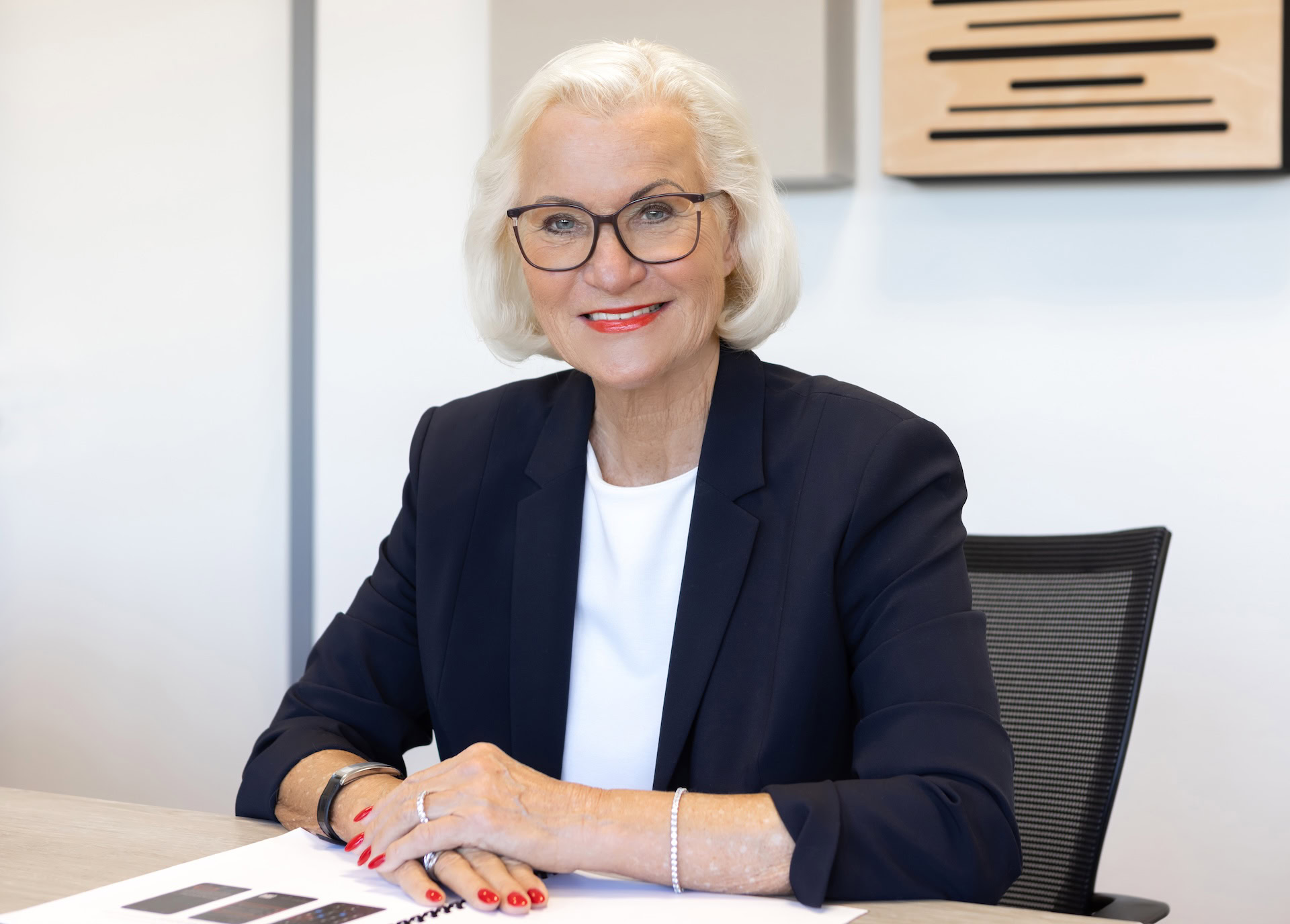 Sigrid Baum, Pressesprecherin der Stadtwerke Jülich, sitzt am Tisch und lächelt in die Kamera